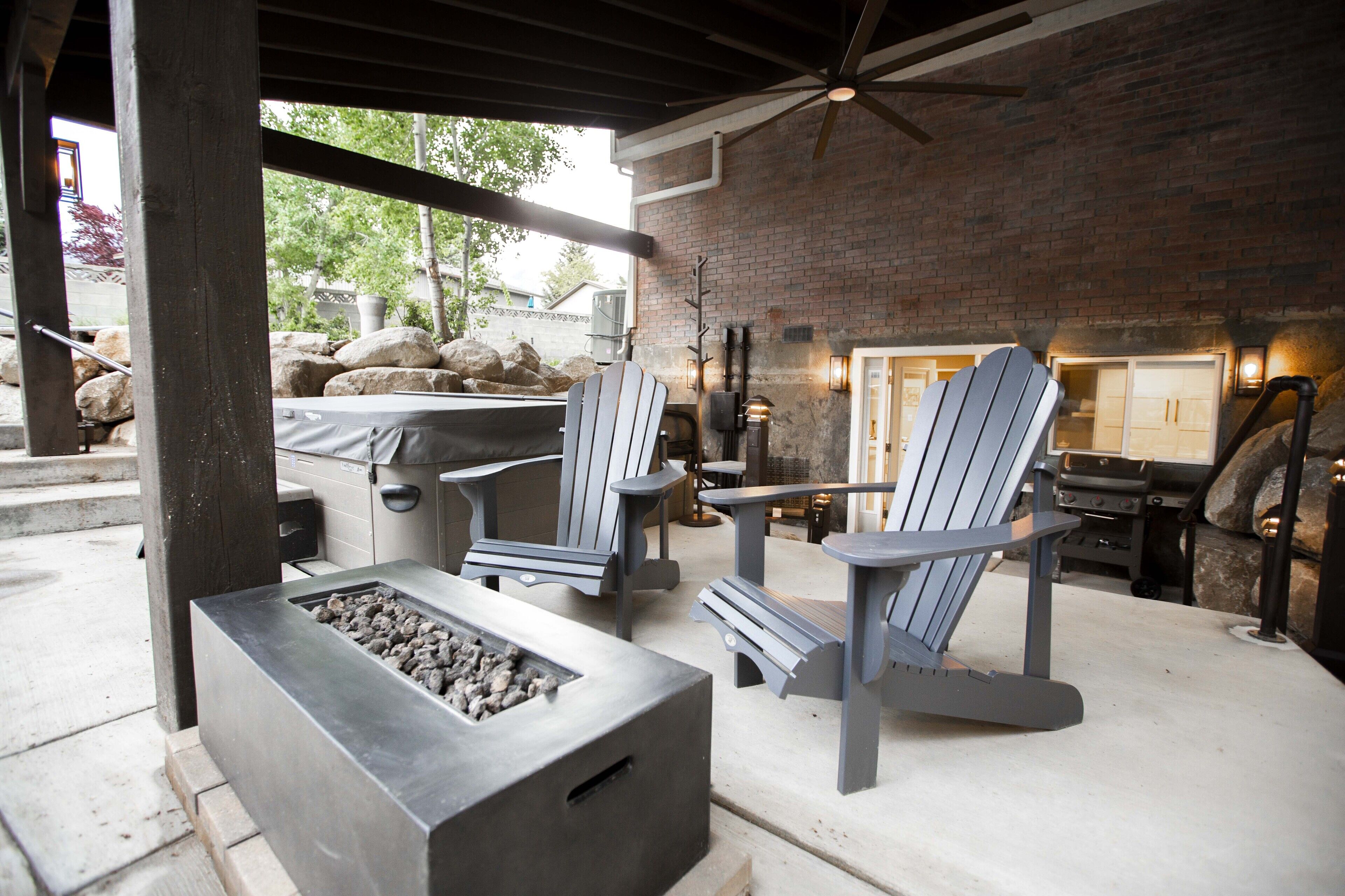 Un espace extérieur aménagé en terrasse, avec des fauteuils Adirondack, un foyer et un mur en briques.