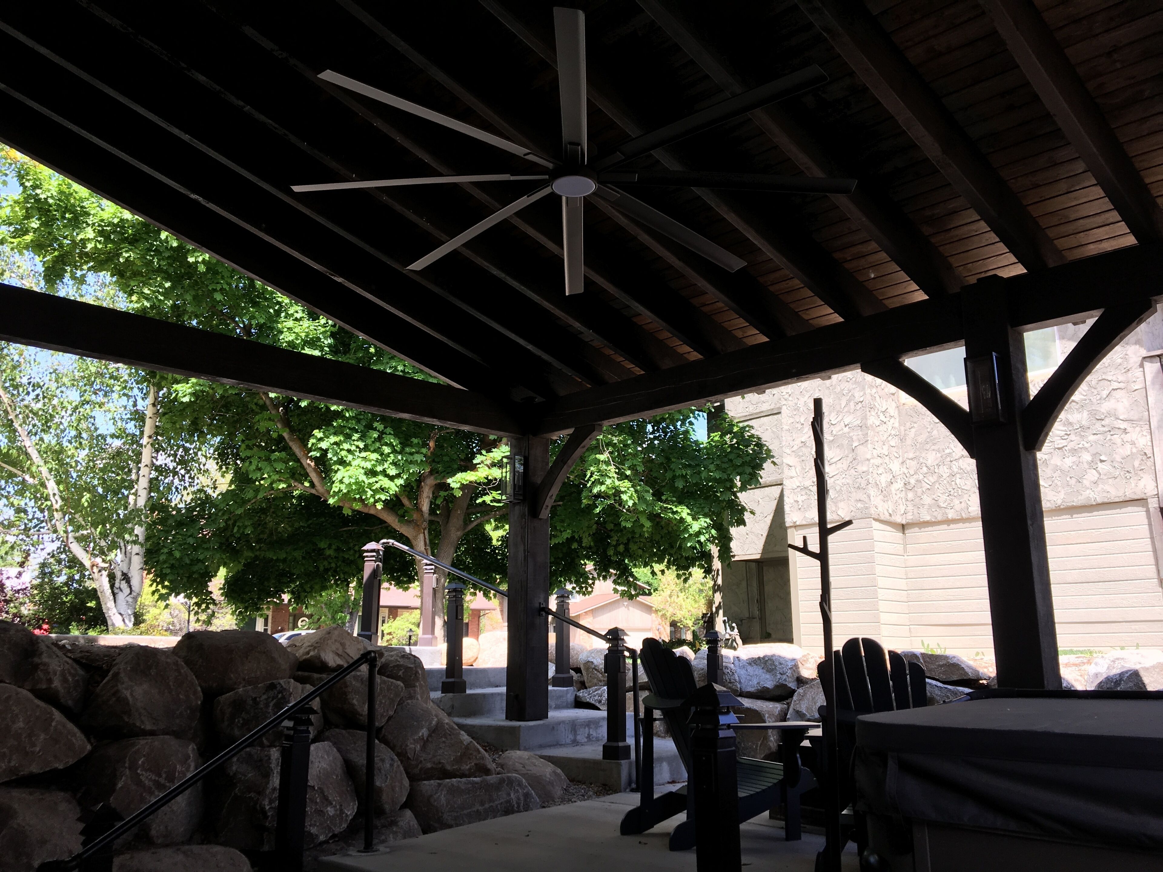 A covered outdoor area with a ceiling fan, stone steps, and outdoor seating.