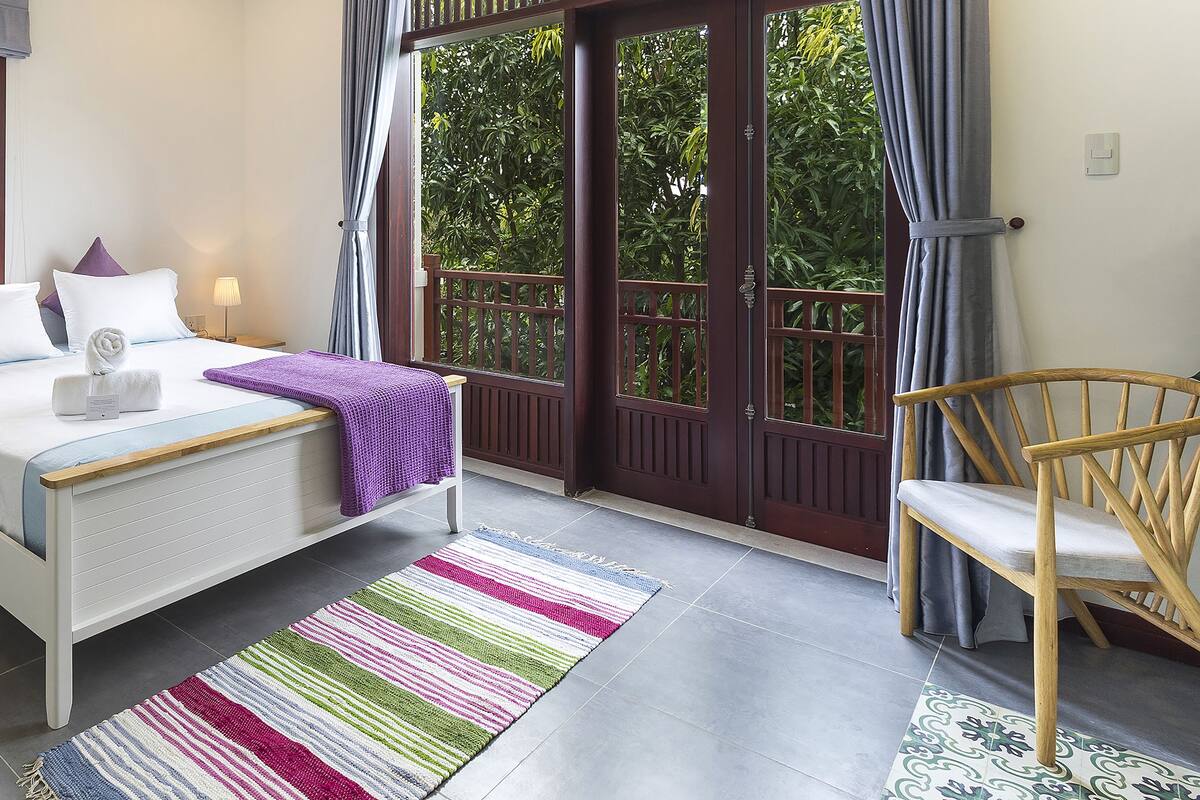 A bedroom with a bed, bedside table, and a chair.
