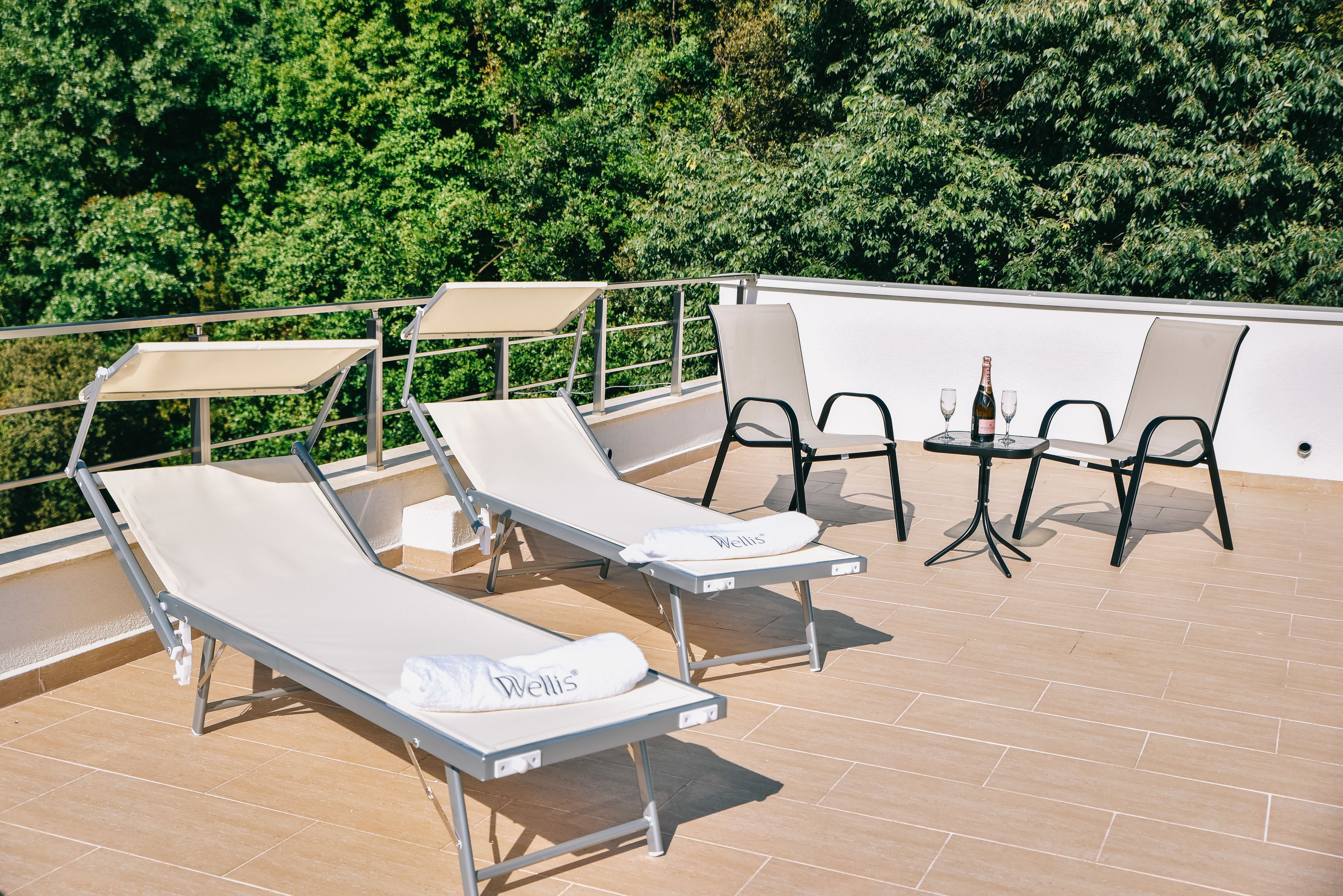 A rooftop terrace with lounge chairs and a table with drinks.