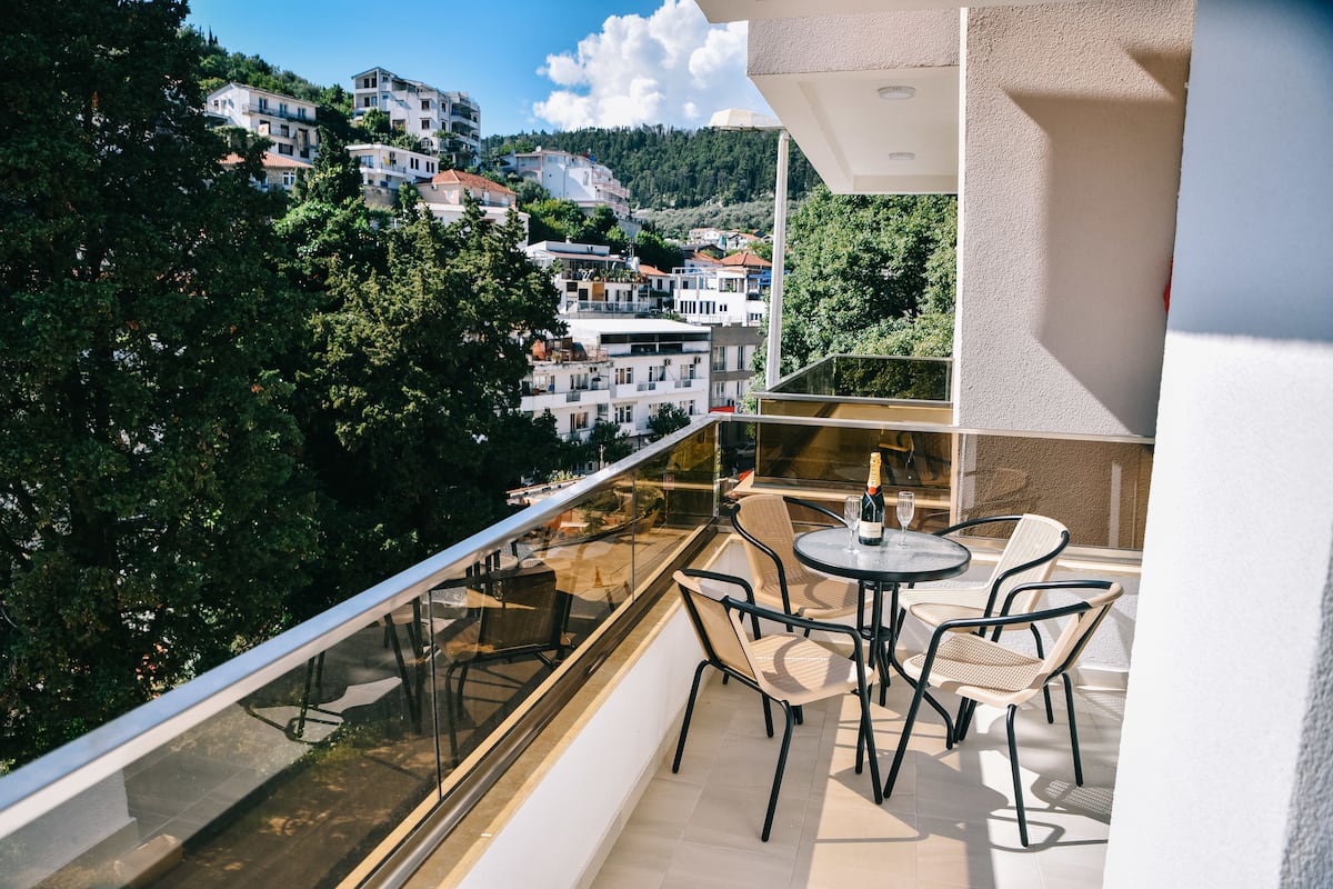 A balcony with a glass railing, a table with chairs, and a bottle of champagne.