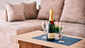 Une bouteille de champagne Moët & Chandon sur une table en bois, avec deux verres, une petite plante et un set de table bleu.
