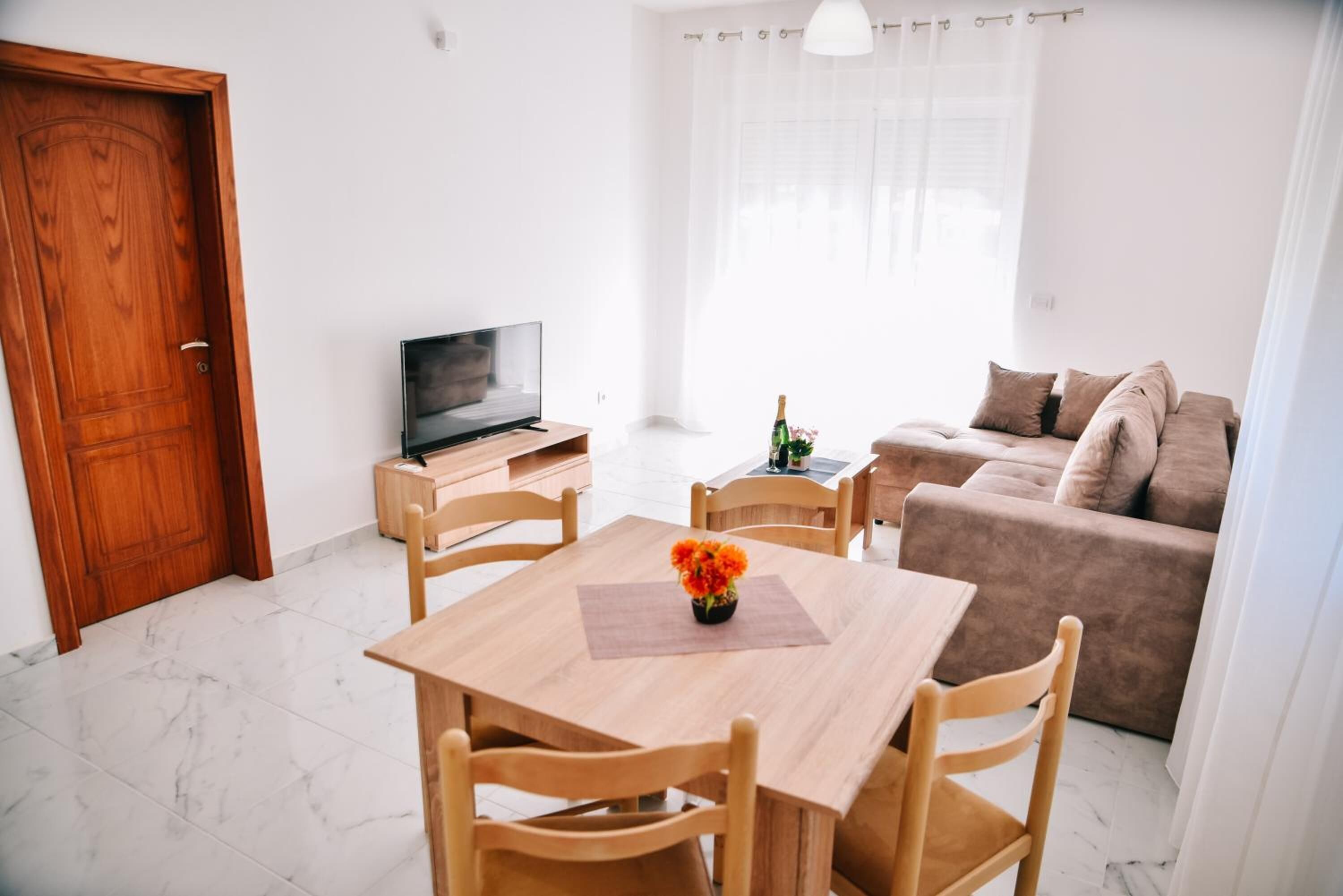 Ein modernes Wohnzimmer mit einem Holzesstisch, einer Couch und einem Fernseher.