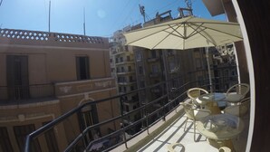 A balcony with a glass table and chairs, an umbrella, and a view of adjacent buildings. - Grand City Hotel (Cairo)