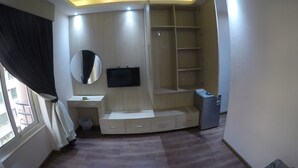 A bedroom with a built-in wardrobe, a mirror, a television, and a small desk area. - Grand City Hotel (Cairo)
