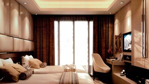 A hotel room with two beds, a desk, a chair, a television, and a large window with curtains. - Grand City Hotel (Cairo)