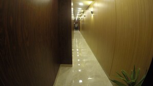 A corridor with wooden walls and a shiny tiled floor, leading to a room with a plant. - Grand City Hotel (Cairo)