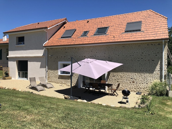 A house with a tiled roof, a patio with a table and chairs, and a small garden area. - Renovated 3 épis barn with 1 to 2 air-conditioned bedrooms for 2 to 6 people. (ASTIS)