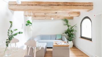 Una sala de estar moderna con techo de madera, un sofá azul claro, una mesa de centro de madera y una planta en maceta.