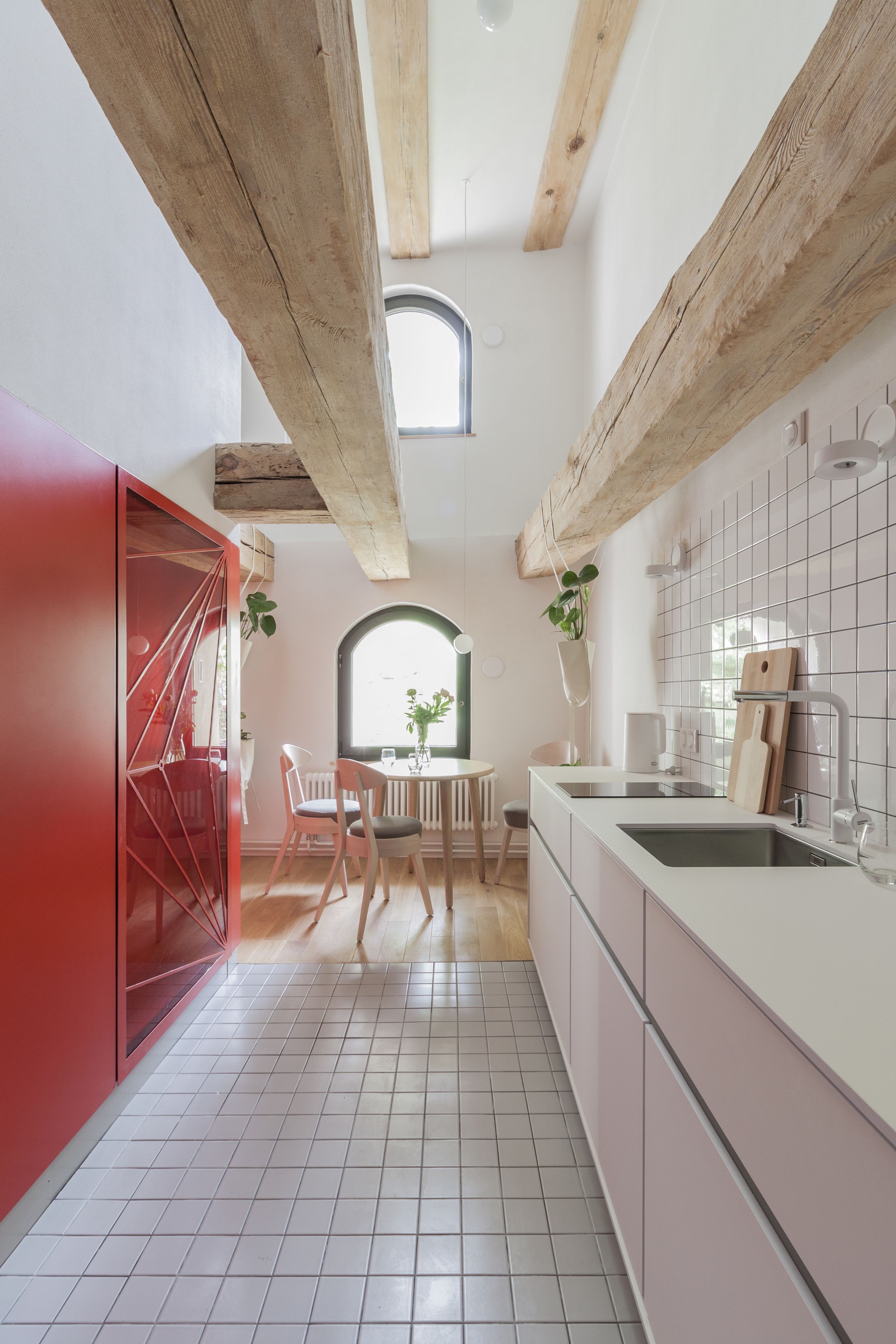 Cozinha moderna com azulejos brancos, vigas de madeira e um armário vermelho.
