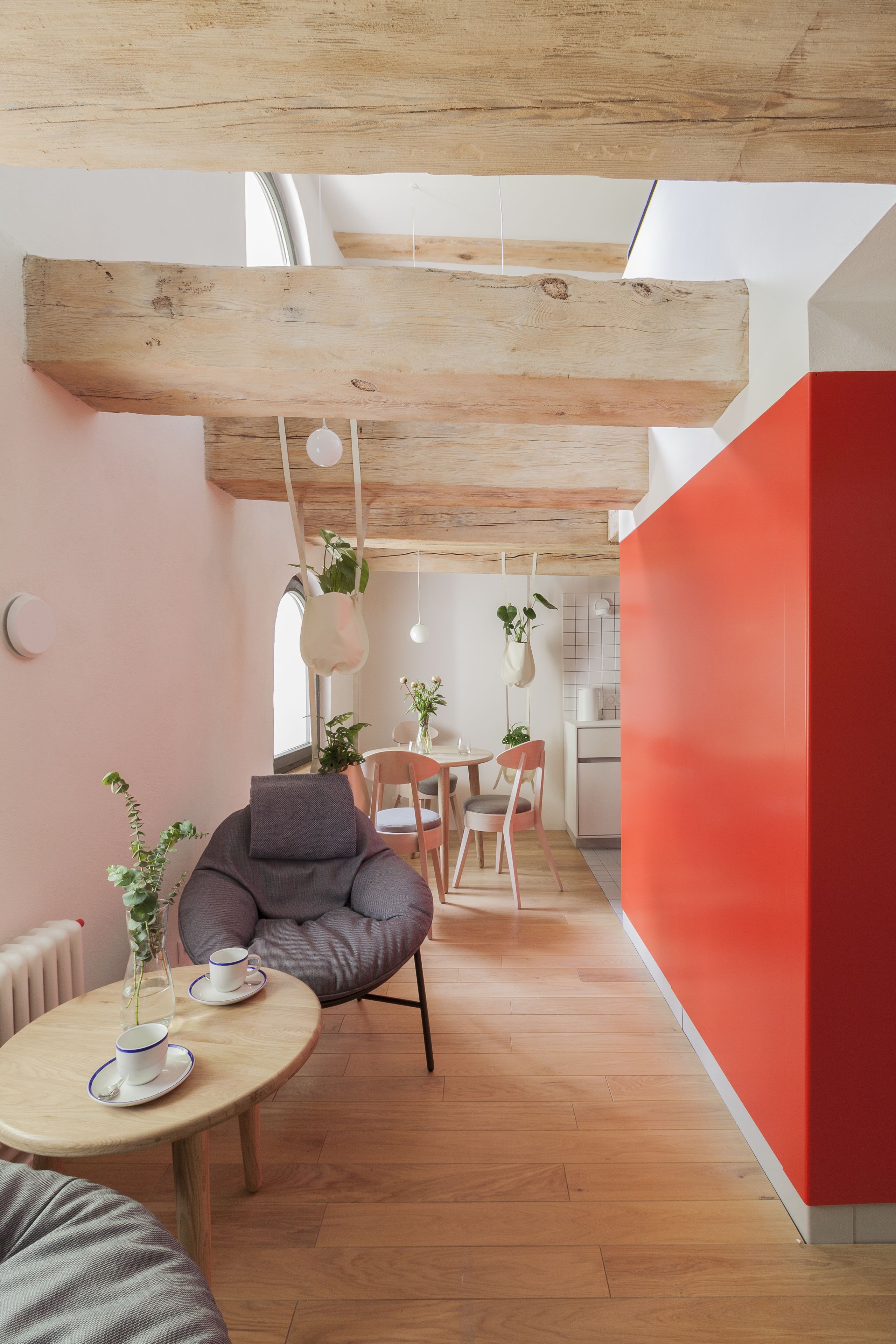 A modern interior with a wooden ceiling, a dining area with a table and chairs, and a kitchen in the background.