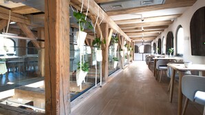 Un interior largo de madera con techos altos, ventanas grandes y plantas colgantes.