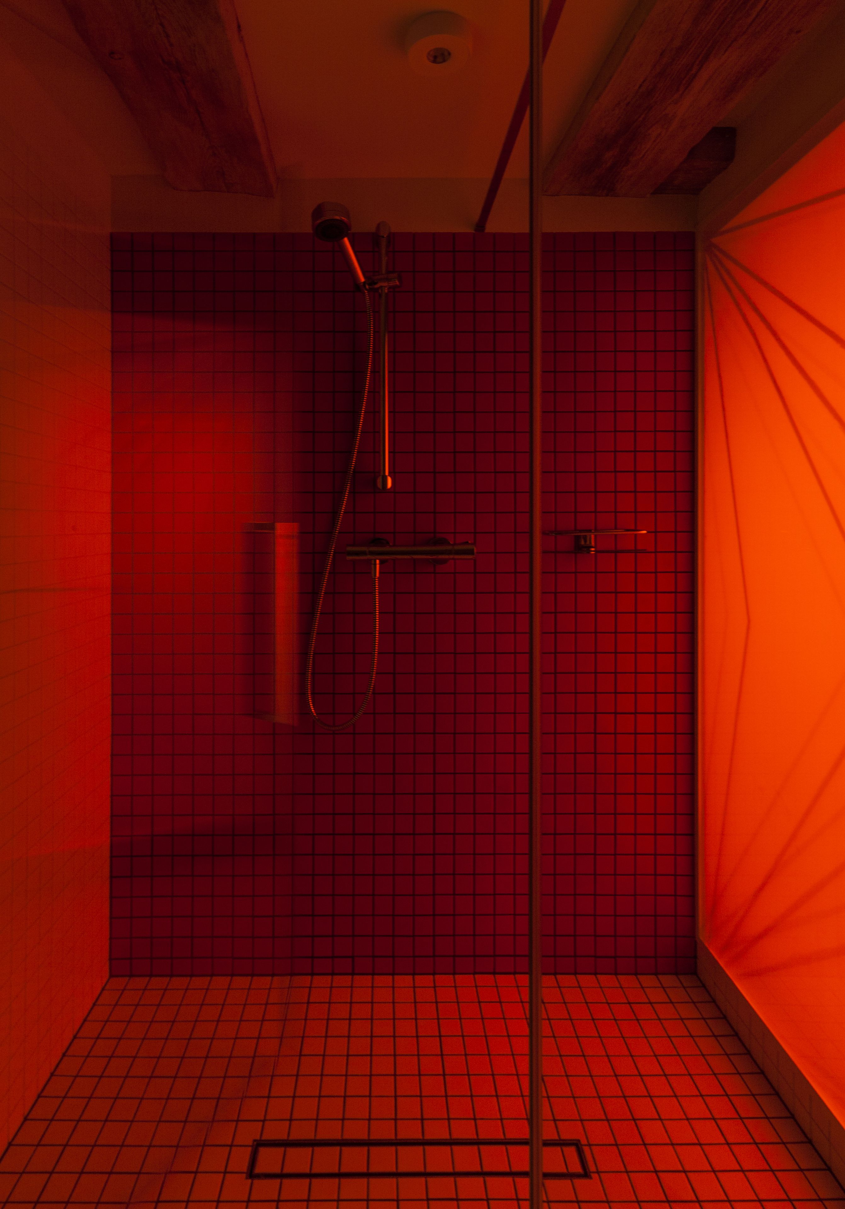 A small, tiled bathroom with a shower and a towel rack.