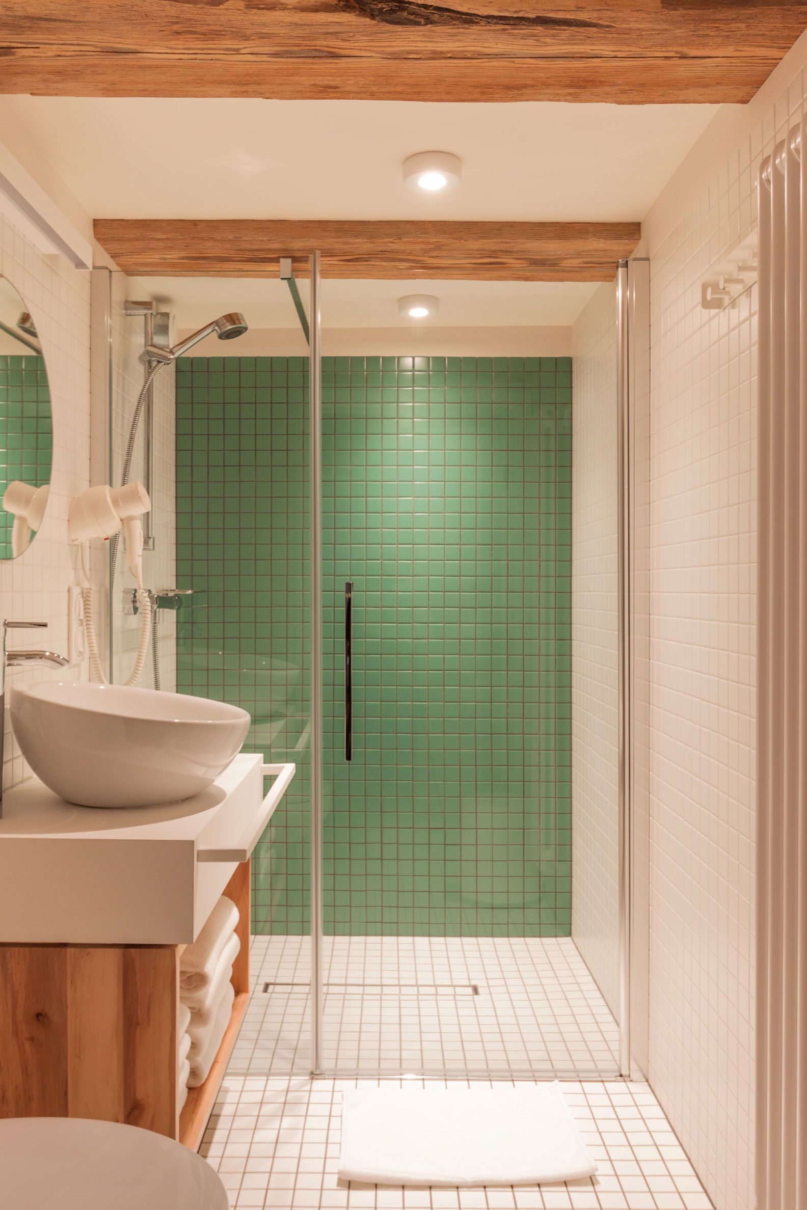 A modern bathroom with a white sink, wooden vanity, and a glass shower enclosure.