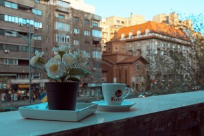 A potted plant and a cup with the logo "Fantim" on a table outside a building with multiple windows and balconies. - Maxxy Apartments (Bucharest)