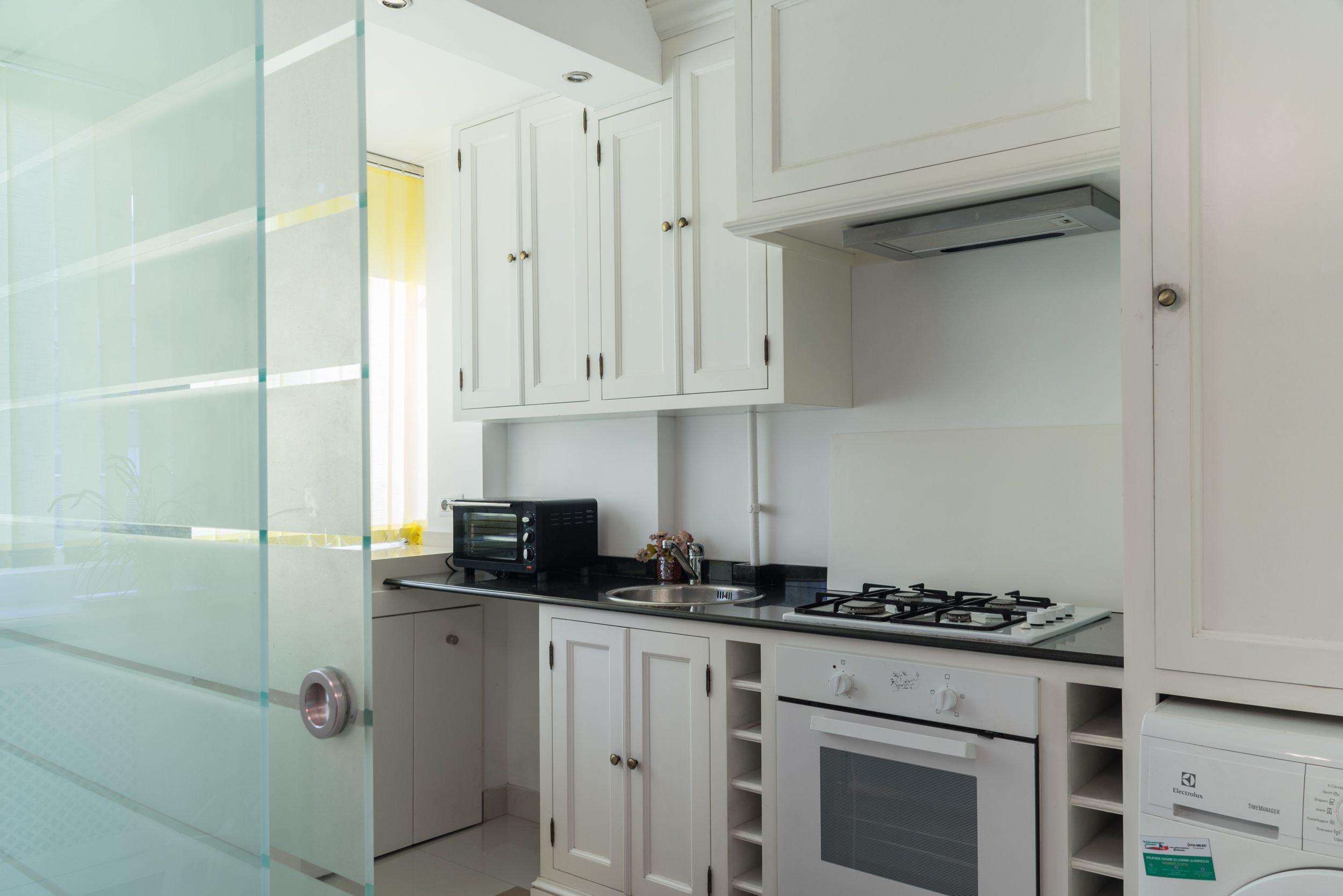 A compact kitchen with white cabinets, a built-in oven, a microwave, and a gas stove.