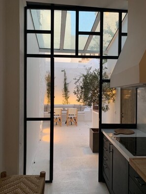 Una cocina moderna con un ventanal grande, un comedor con sofá y sillas, y una mesa pequeña.
