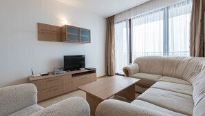 Een moderne woonkamer met een bank, een salontafel en een televisie op een houten kast.