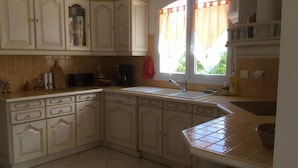 A kitchen with white cabinets, a sink, and a window with curtains. - 240m2 family villa with swimming pool (Sorede)
