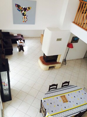 Cozy living area with a high ceiling, modern fireplace, and dining table for two.