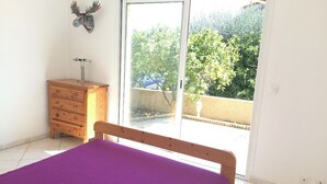 A bedroom with a bed, wooden dresser, and a sliding glass door to a balcony. - 240m2 family villa with swimming pool (Sorede)