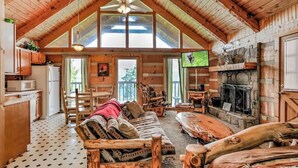 A log cabin interior with a high ceiling, a fireplace, a television, and a dining area. - View! Private Studio Cabin,Hot Tub,RELAX,Honeymoon (Sevierville)