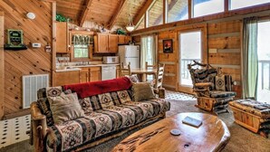 A cozy cabin interior with a wooden ceiling, a sofa, a coffee table, a dining table, and a kitchen area. - View! Private Studio Cabin,Hot Tub,RELAX,Honeymoon (Sevierville)