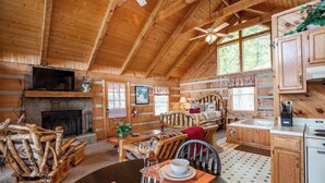 A cozy cabin interior with a fireplace, wooden furniture, a dining area, and a kitchen. - View! Private Studio Cabin,Hot Tub,RELAX,Honeymoon (Sevierville)
