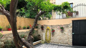 A courtyard with a stone wall, potted plants, and a tiled floor.