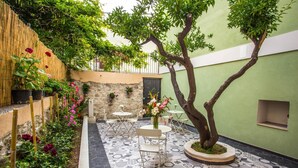 A courtyard with a tiled floor, a tree, and potted plants.