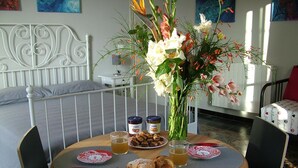 A breakfast setup with croissants, jam, and a floral centerpiece on a round table.