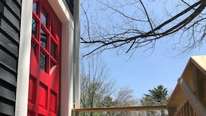 A wooden deck with a red door, a welcome mat, and a potted plant. - THE BARN ON PASCAL... A lovely circa 1900 refurbished barn. (Rockport)