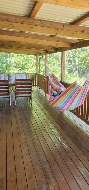 A wooden deck with a hammock, wooden chairs, and a table. - All year round villa near the beach. (Mönsterås)