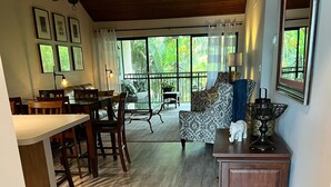 A spacious living area with a dining table and chairs, a sofa, and a kitchen area with a wooden cabinet. - Luxurious Beach Resort Atmosphere Getaway (Fort pierce)