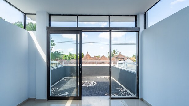 A room with a large sliding glass door leading to a balcony with a patterned floor. - OYO 672 Bali Radiance Canggu (Tibubeneng)