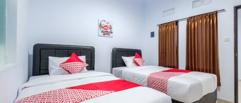 A hotel room with two beds, each with a black headboard, white bedding, and red accents.