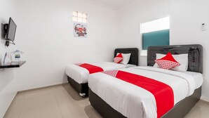 A hotel room with two beds, a TV, a small shelf with a water bottle, a window, and an air conditioning unit. - OYO 672 Bali Radiance Canggu (Tibubeneng)