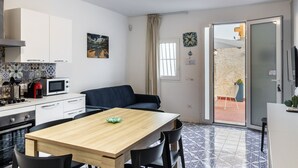 A compact kitchen with a dining area, a blue sofa, and a view of the outdoor patio.