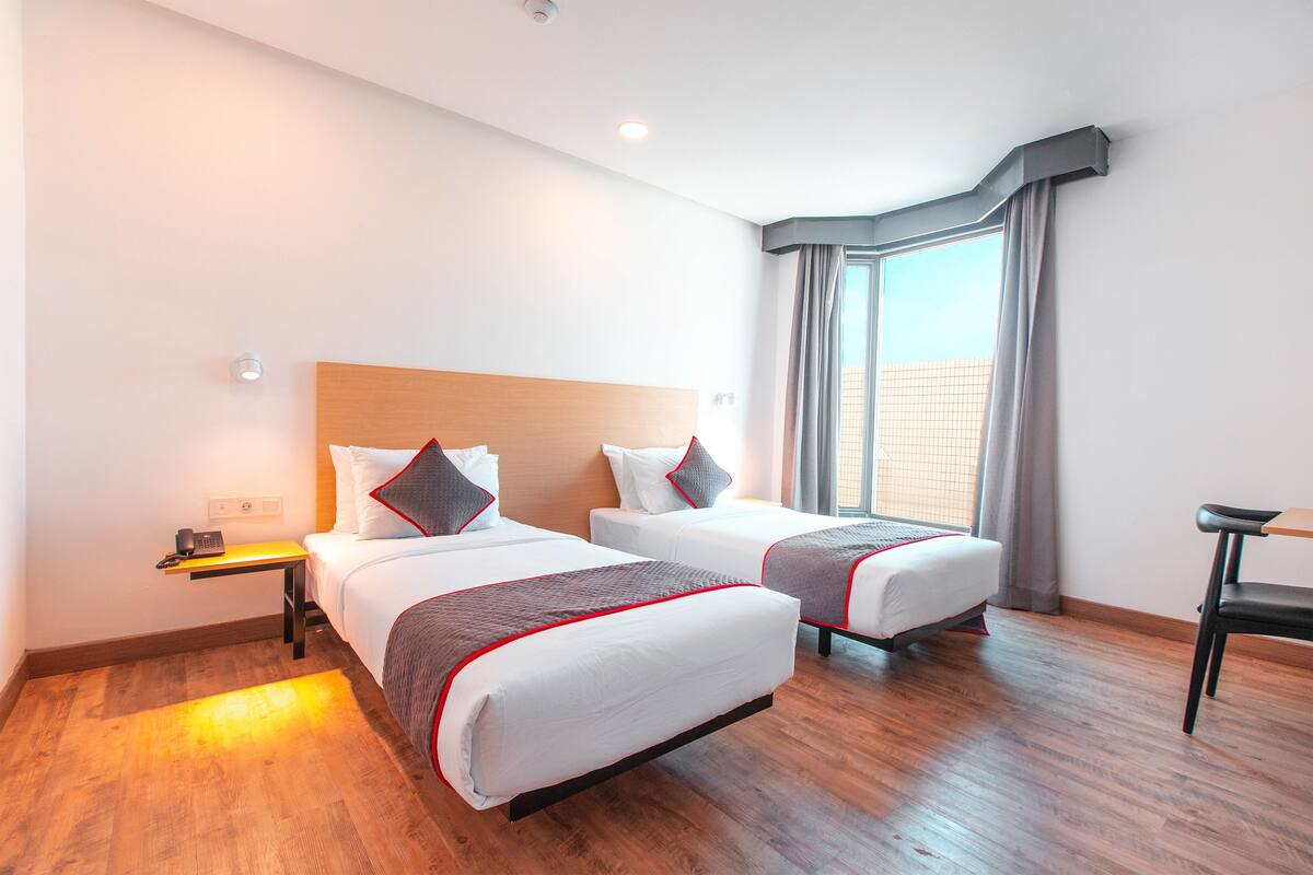 A hotel room with two beds, a desk, and a chair.