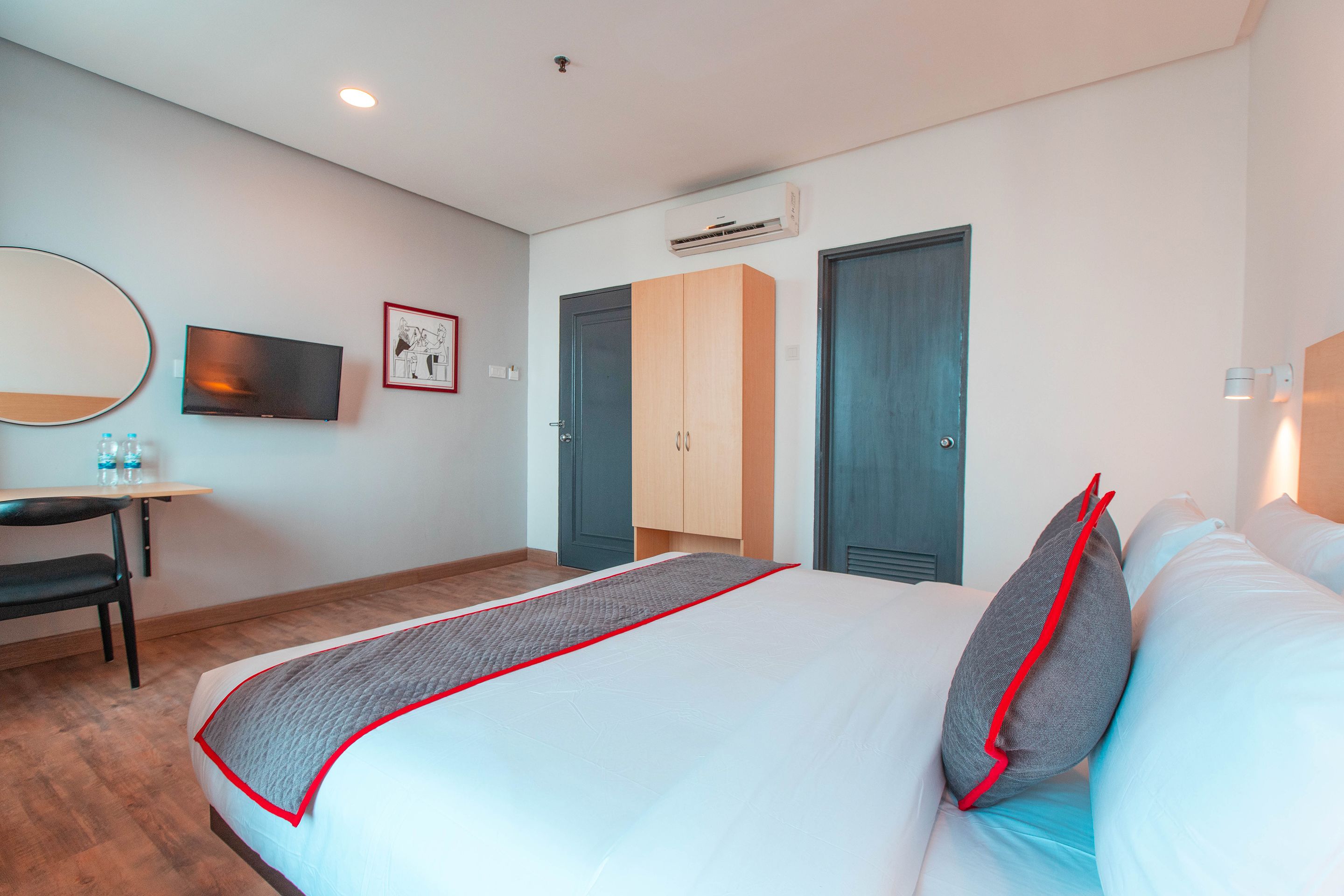 Habitación de hotel con cama, escritorio, silla, televisor y armario.