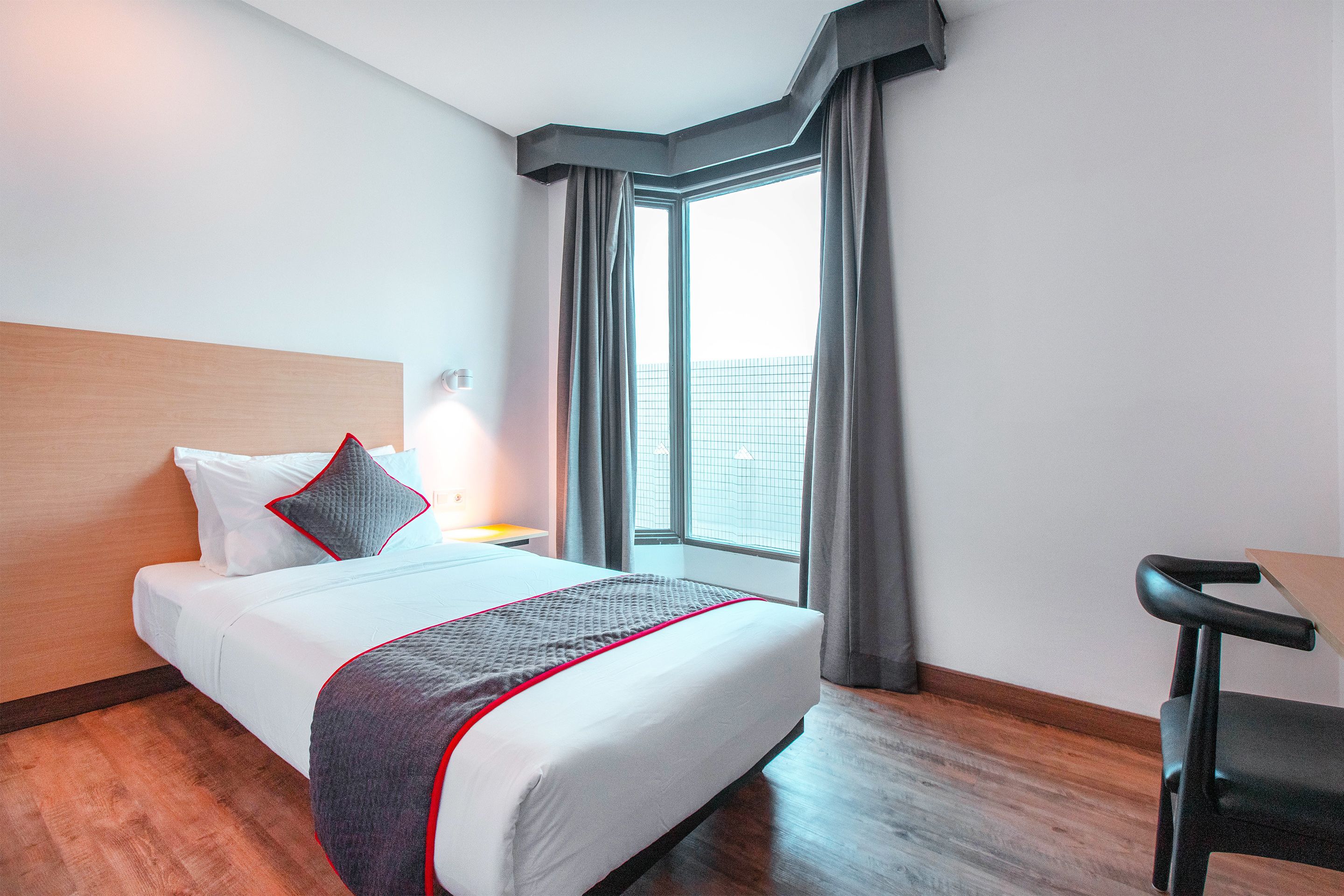 Ein Hotelzimmer mit einem großen Bett, einem Schreibtisch und einem Fenster mit Vorhängen.