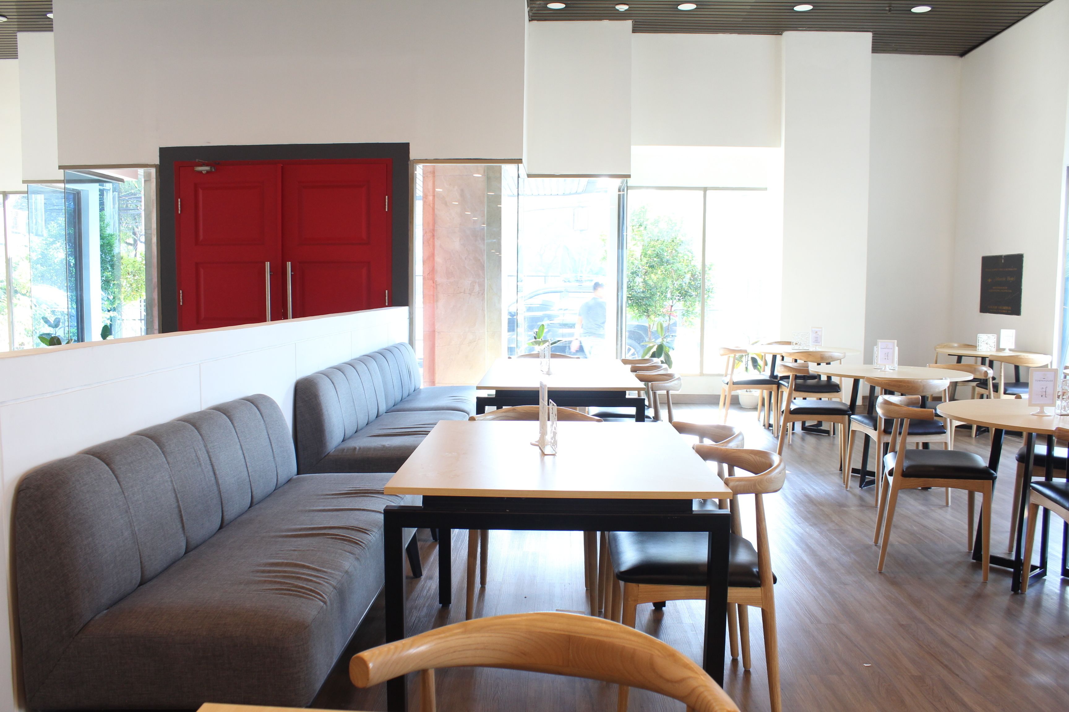 A modern restaurant with a long grey bench, wooden tables, and chairs.