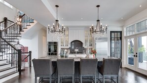 A spacious kitchen with a central island, dark wood flooring, and a chandelier.
