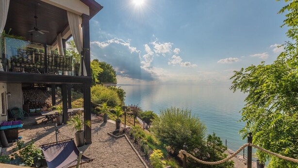 A lakeside property with a covered outdoor area, a dining setup, and a view of the lake.