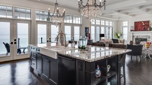 A spacious kitchen with a large island, dark cabinetry, and a view of the ocean through large windows.