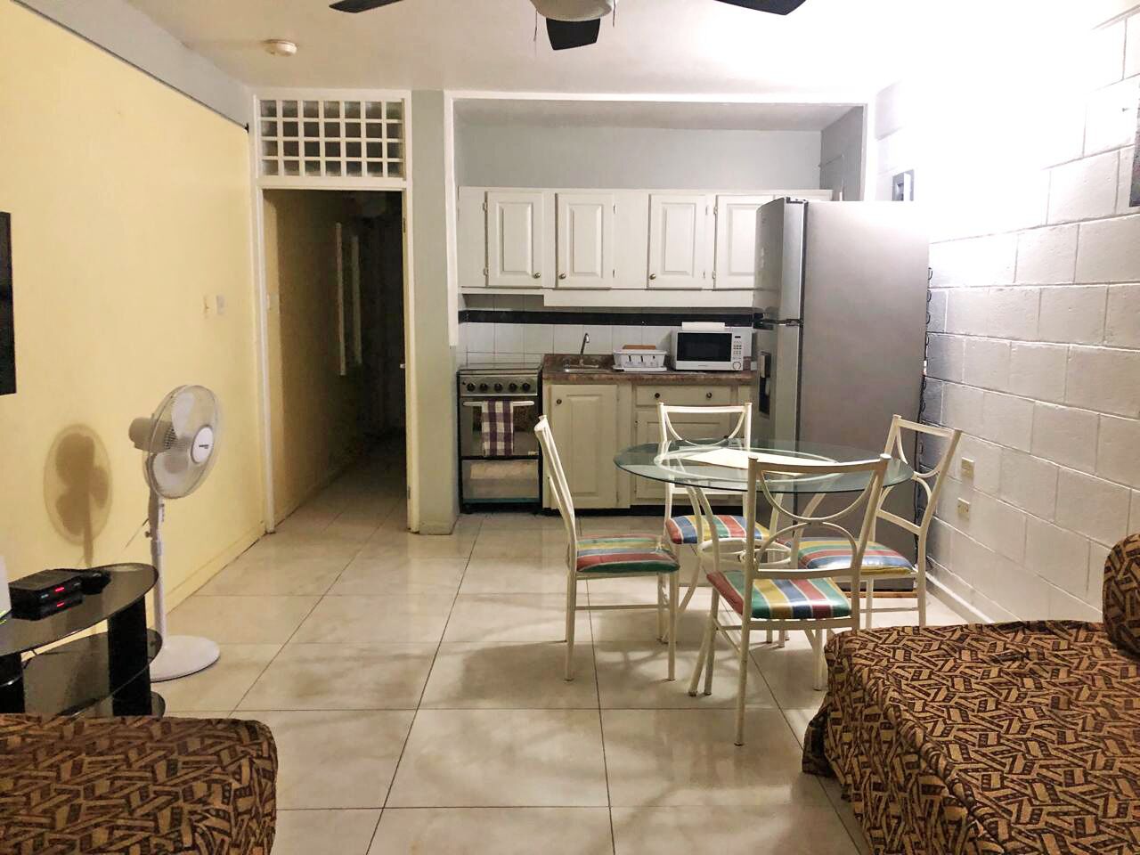 Un espace de vie compact comprenant un coin repas, une kitchenette et un ventilateur.