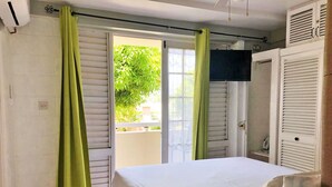 Ein Schlafzimmer mit einem Bett, einem Fenster mit grünen Vorhängen, einer Tür und einer weißen Wand.