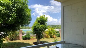 Ein Balkon mit Glastisch und Stühlen, der einen Blick auf ein Schwimmbad und üppige Bepflanzung bietet.