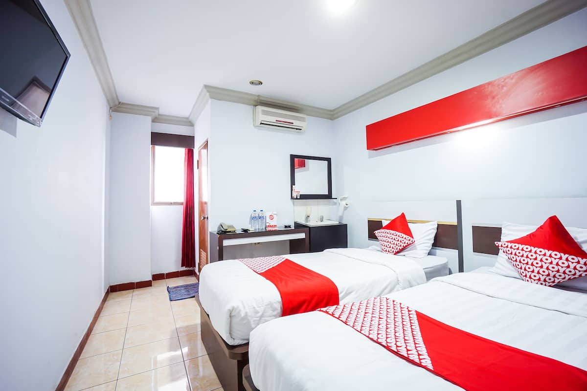 Habitación de hotel con dos camas, un escritorio, un espejo y un televisor.