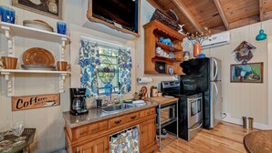 A kitchen with wooden cabinets, a coffee shop sign, a stove, and a refrigerator. - Amazing Mountain Views Special Rates Book Today (Mentone)